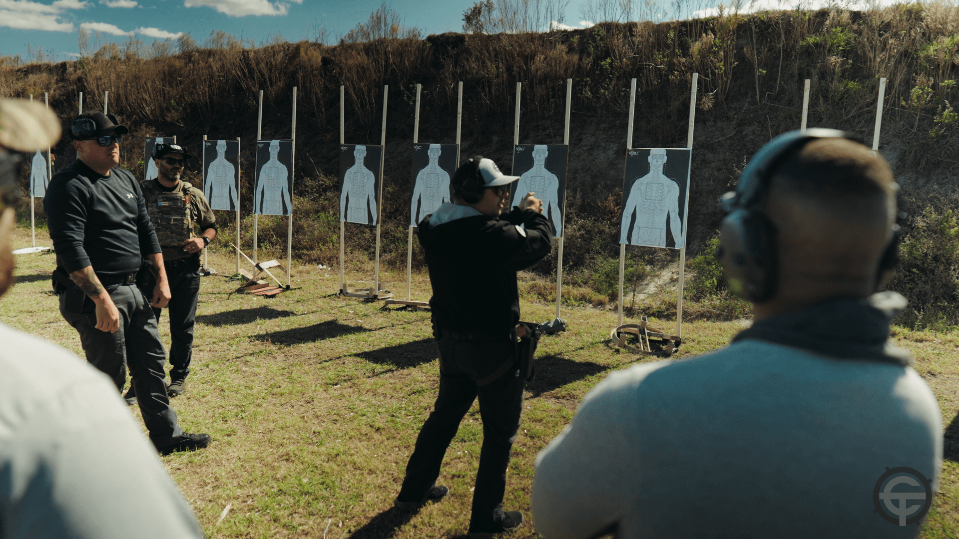 Josiah demonstrating technique to students with silhouette targets at outdoor range
