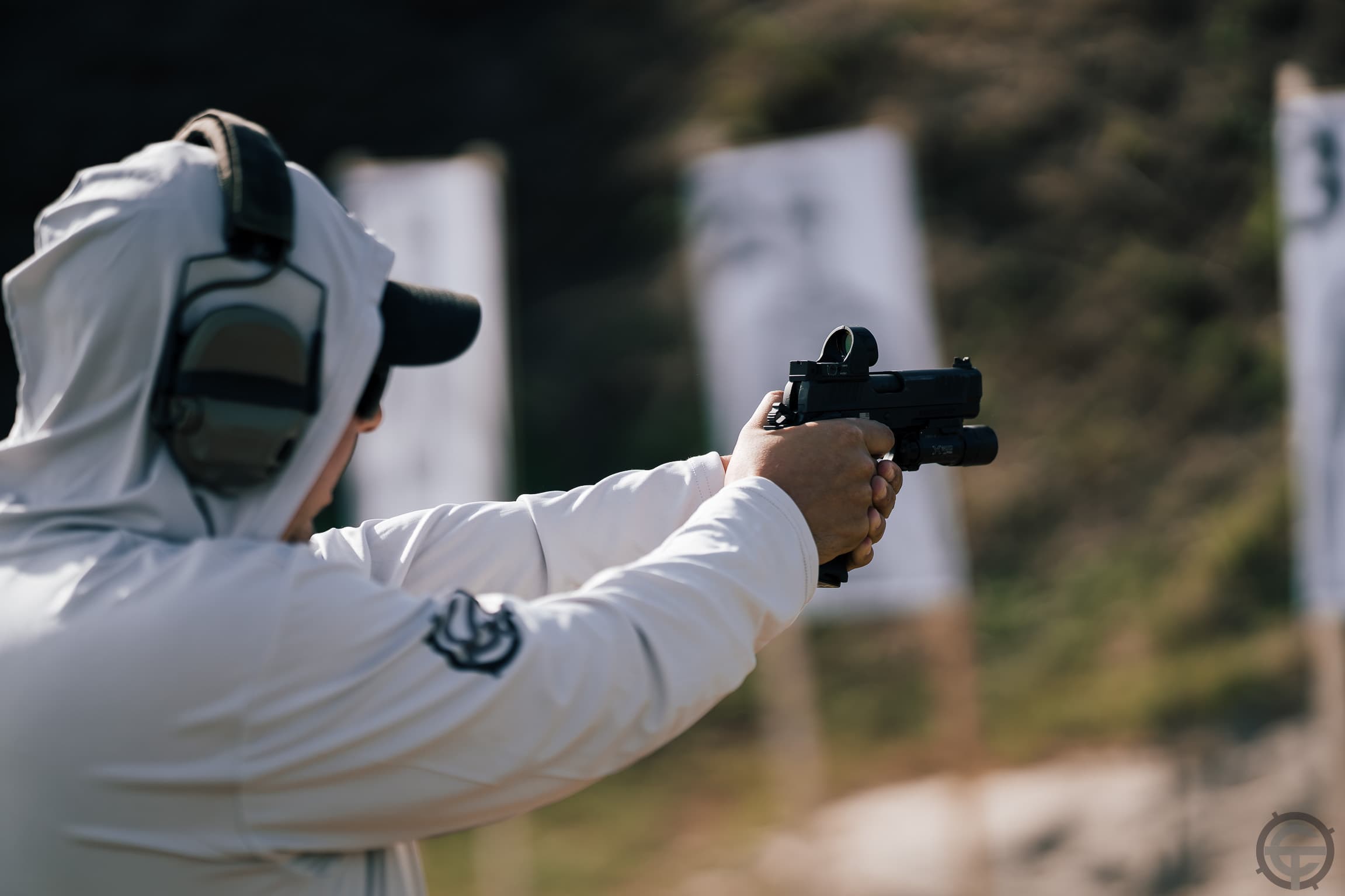 Instructor firing pistol with red dot downrange during Pistol Workshop