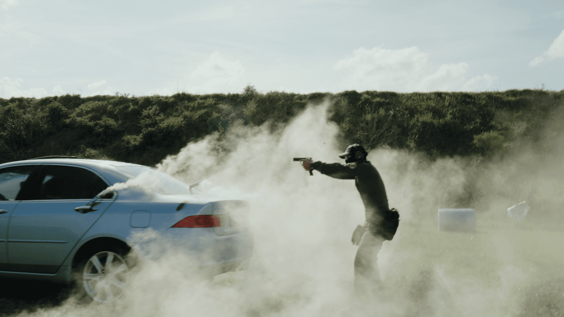 Tactical shooter emerging from behind vehicle in smoke during force-on-force drill